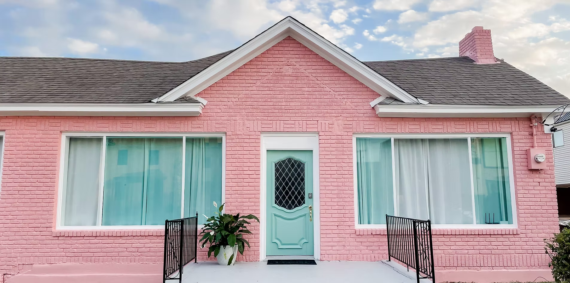 The pink brick exterior of The Galiston House with a mint front door