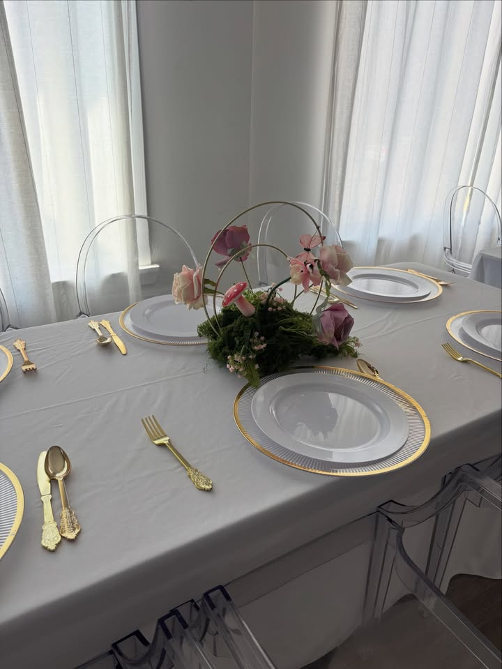Long dinner table with gold flatware, gold-rim chargers and floral centerpiece