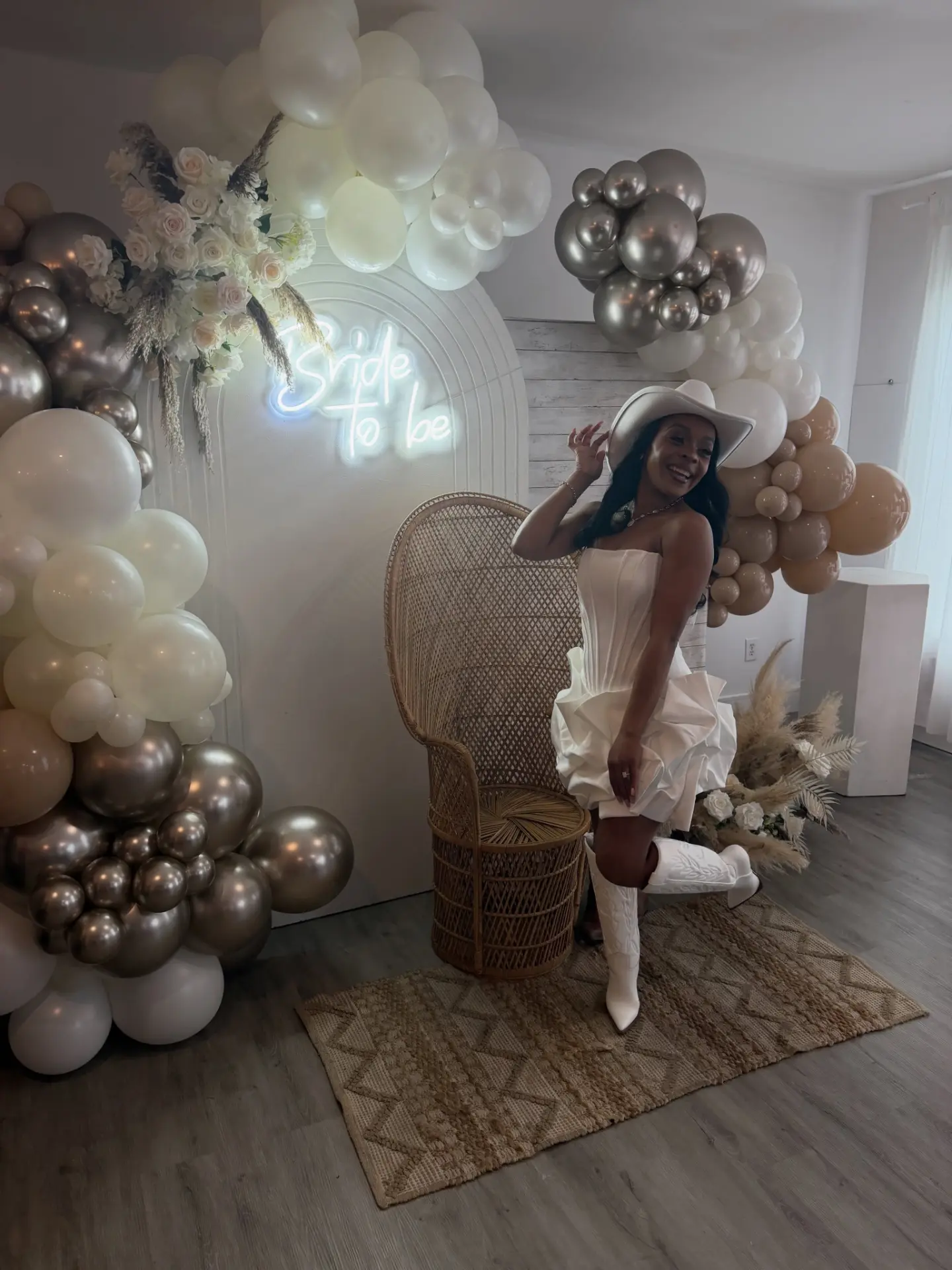 Bride-to-be balloon garland setup with neon sign and peacock chair